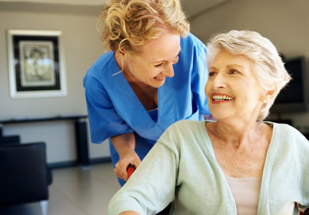 A carer embraces an older woman, showcasing a moment of warmth and affection between them