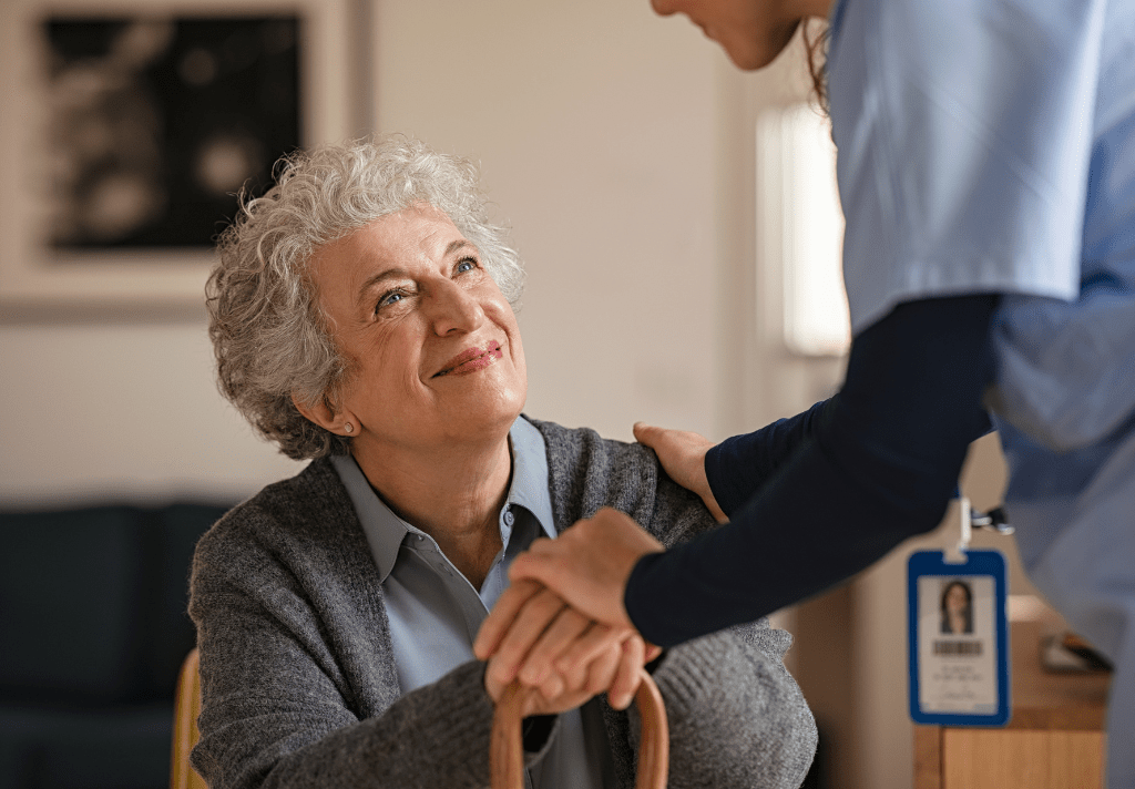 A compassionate nurse gently holds the hand of an elderly woman, symbolising care and support in a healthcare setting.