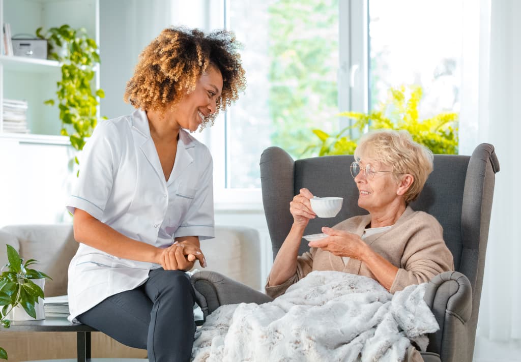 A woman assists an elderly woman in a wheelchair, showcasing compassion and support in a caring environment.