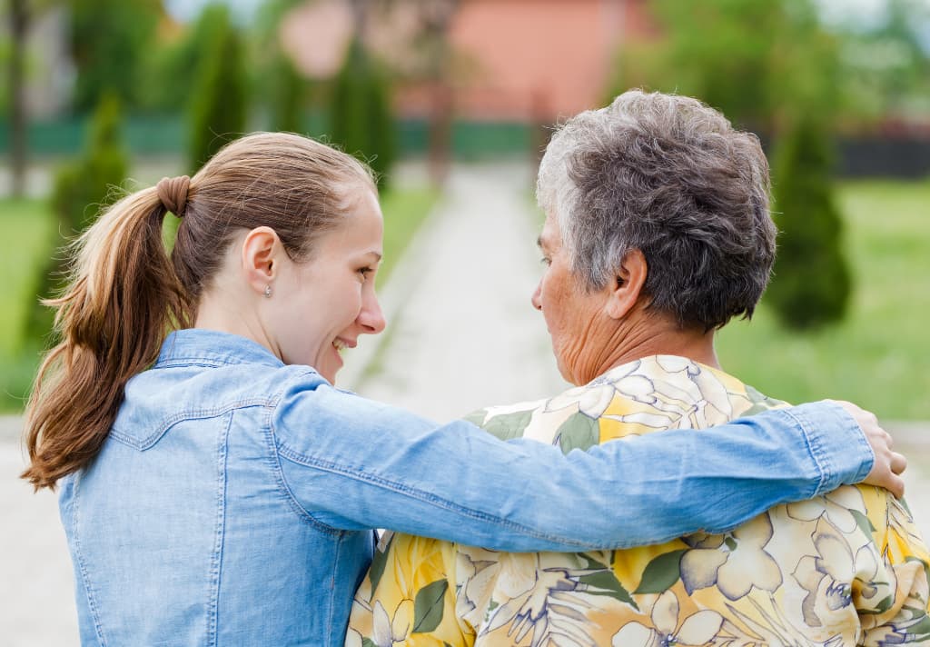 A woman embraces an older woman, using storytelling to connect with ageing family members 