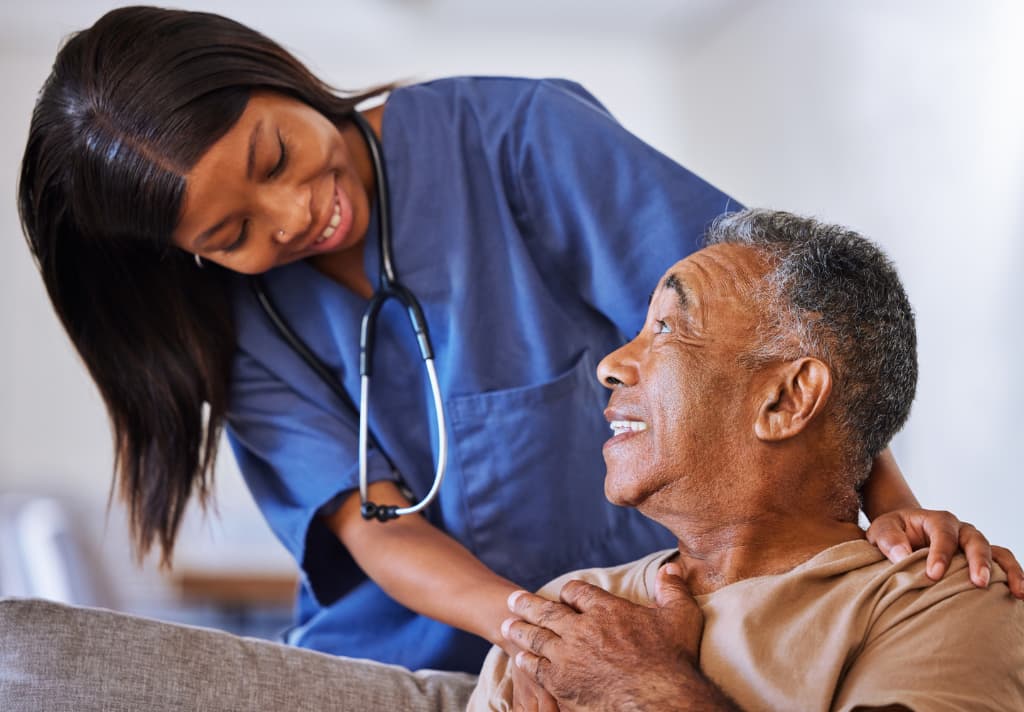 A nurse assists an elderly man, providing care and support in an adult care home setting