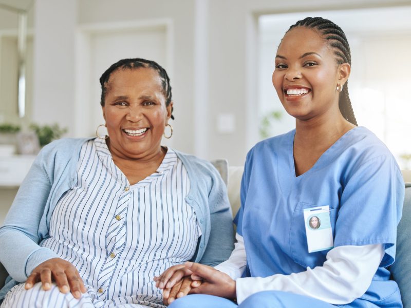 A-senior-woman-and-a-nurse-holding-hands-in-a-care-home-and-both-are-smiling-scaled.jpg